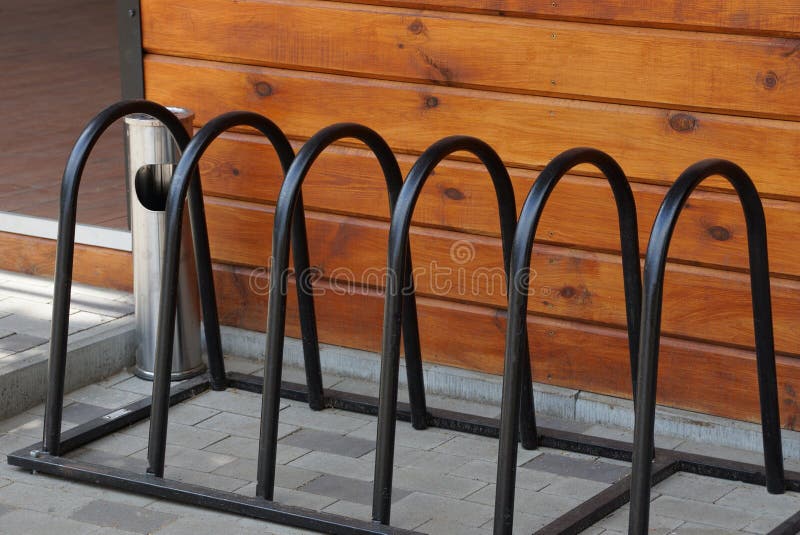 En rad av svarta metallstänger av en cykelparkering på trottoaren royaltyfri foto En rad av svarta metallstänger av en cykelparkering på trottoaren royaltyfri foto