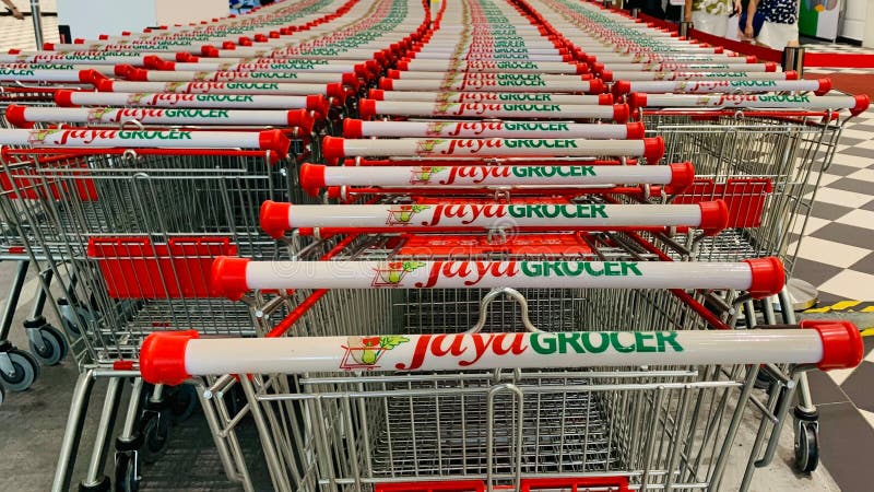 A row of shopping carts with the word "Jaya Grocer" on them. The carts are lined up in a store. A row of shopping carts with the word "Jaya Grocer" on them. The carts are lined up in a store