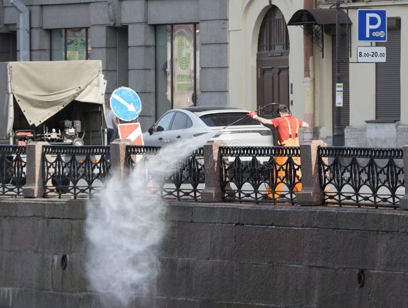 A cleaner in an orange vest washes the embankment with water from a hose, Moika River Embankment, St. Petersburg, Russia, April 29, 2024. A cleaner in an orange vest washes the embankment with water from a hose, Moika River Embankment, St. Petersburg, Russia, April 29, 2024