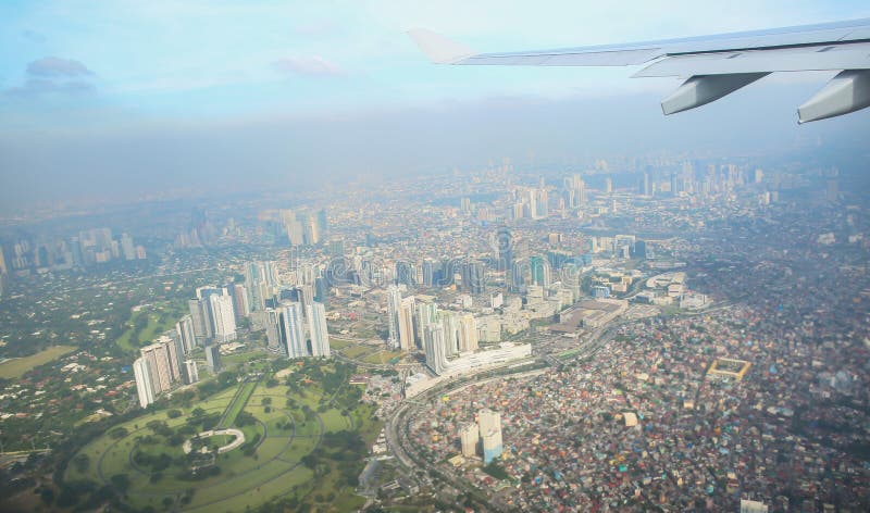 En sikt av staden av Manila till och med fönstret från nivån Imponerat foto av en turist i flykten över huvudstaden royaltyfria bilder En sikt av staden av Manila till och med fönstret från nivån Imponerat foto av en turist i flykten över huvudstaden royaltyfria bilder
