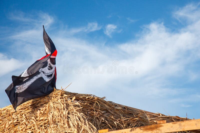 En skalle och korslagda benknotor piratkopierar flaggan som vinkar i vinden , Piratkopierar Jolly Roger, flaggan arkivfoto En skalle och korslagda benknotor piratkopierar flaggan som vinkar i vinden , Piratkopierar Jolly Roger, flaggan arkivfoto