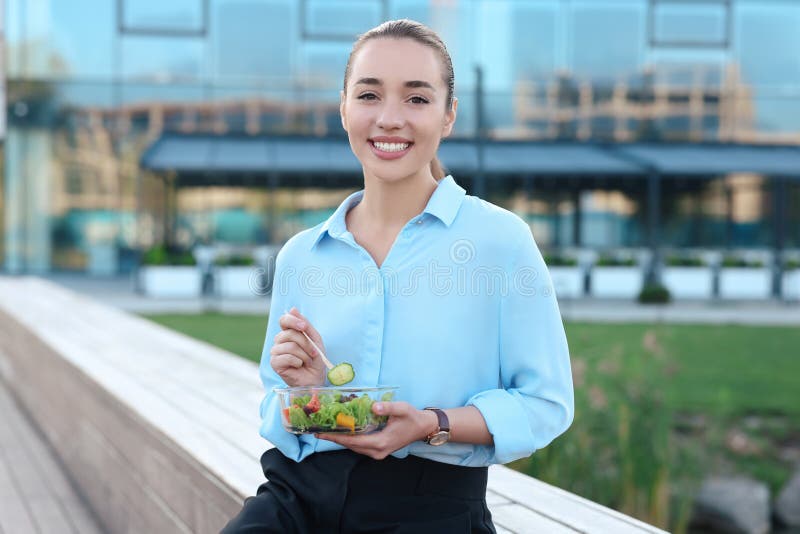 En skildring av leende affärskvinna som äter lunch utomhus royaltyfria foton