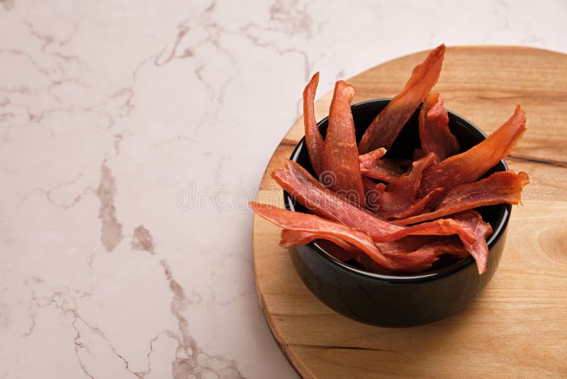 En skål av jerky-chips på en lätt marmor bakgrund arkivfoto