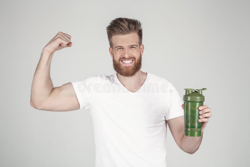 En st?ende av en h?rlig man med ett sk?gg och en trendig frisyr, ikl?dda tillf?lliga kl?der, rymmer en sportshaker och arkivbilder En st?ende av en h?rlig man med ett sk?gg och en trendig frisyr, ikl?dda tillf?lliga kl?der, rymmer en sportshaker och arkivbilder
