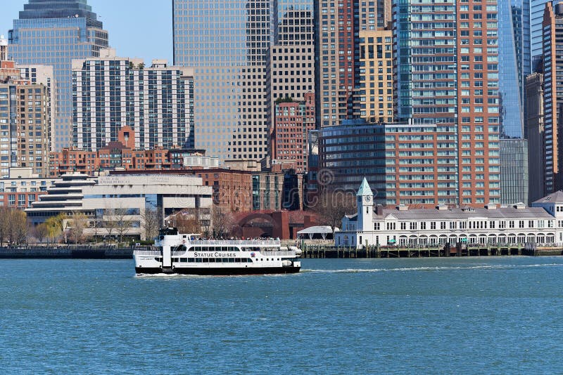 New York, NY - April 6, 2021: A Statue Cruises ferry leaves from Lower Manhattan taking tourists to the Statue of Liberty. In the background is the Holocaust Museum, Pier A and the skyscrapers of Lower Manhattan, NYC. New York, NY - April 6, 2021: A Statue Cruises ferry leaves from Lower Manhattan taking tourists to the Statue of Liberty. In the background is the Holocaust Museum, Pier A and the skyscrapers of Lower Manhattan, NYC