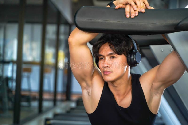 En stilig idrottsman som spelar foto med hörlmusik i gymmet arkivbild
