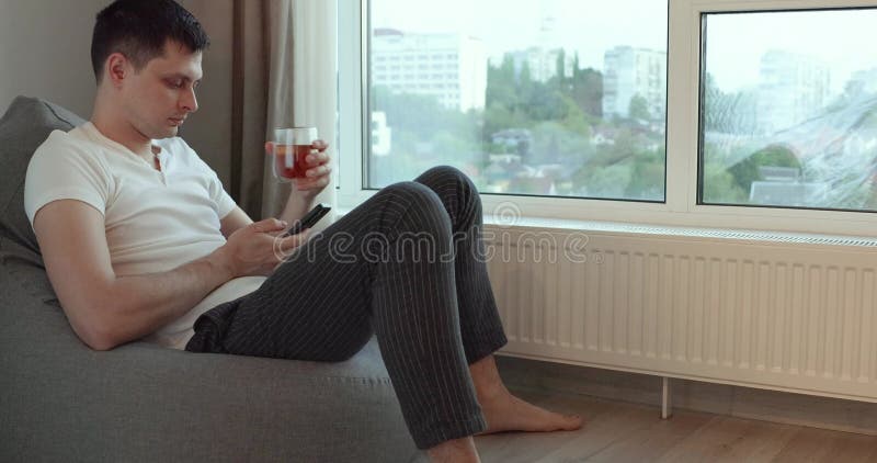 En stilig man som använder telefon och dricker kaffe stock video