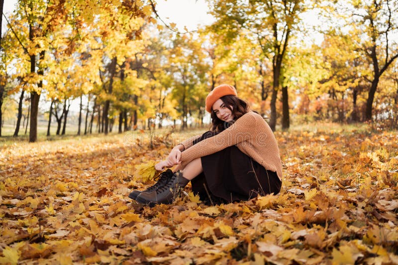 En stilig ung kvinna som får vila med blad i höstparken. relaxering som åtnjuter ensamhet med naturen royaltyfri fotografi