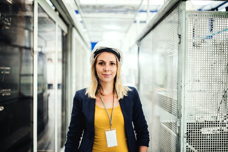 En stående av ett industriellt kvinnateknikeranseende i en fabrik royaltyfri fotografi En stående av ett industriellt kvinnateknikeranseende i en fabrik royaltyfri fotografi