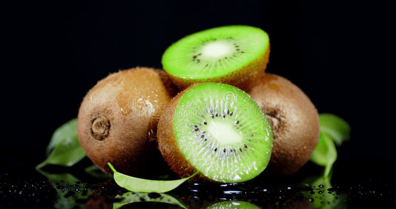 En su totalidad y en rodajas de kiwi fresco con hojas que caen gotas de agua metrajes