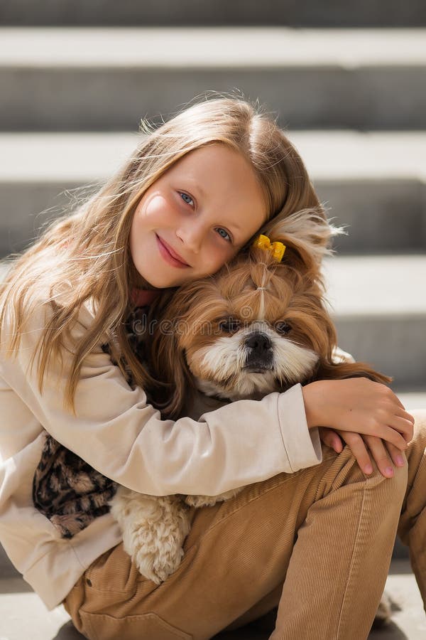 En söt, leende blondinsk flicka på 9 år som varsamt kramar en hund arkivfoton