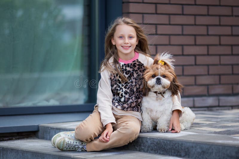 En söt, leende blondinsk flicka på 9 år som varsamt kramar en hund royaltyfri bild