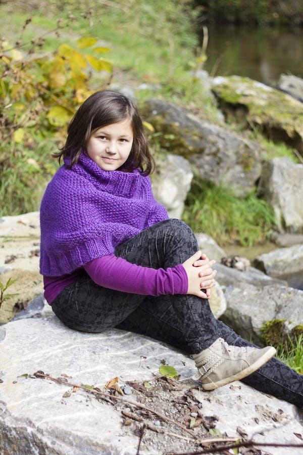 En tonårig flicka med lila poncho royaltyfria foton