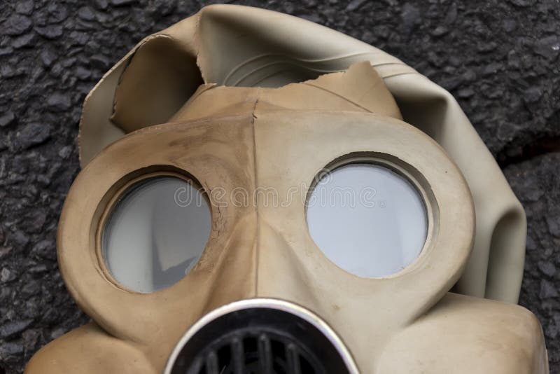En torn mask med rysk gasmask med byggfilter ligger på den texturerade asfalten.. begrepp : slarvig förvaring av militär ammuni royaltyfria foton