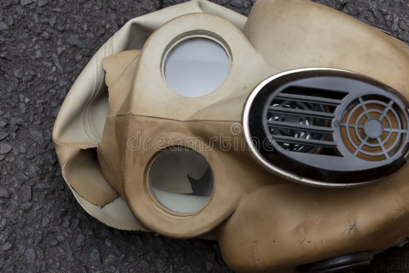 En torn mask med rysk gasmask med byggfilter ligger på den texturerade asfalten.. begrepp : slarvig förvaring av militär ammuni royaltyfri foto