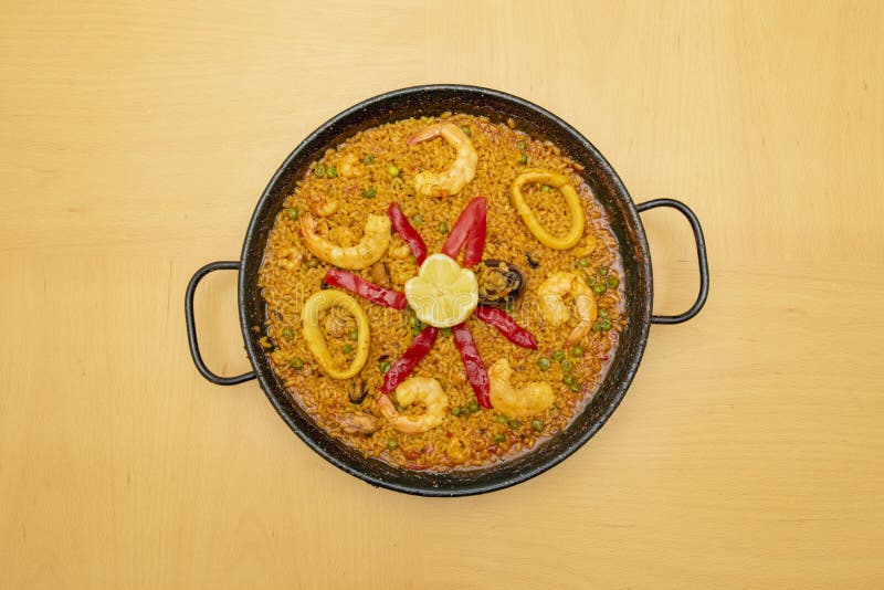 En underbar spansk skaldjur och fiskpaella med rostad röd paprika och en citron i mitten för att garnera royaltyfri foto