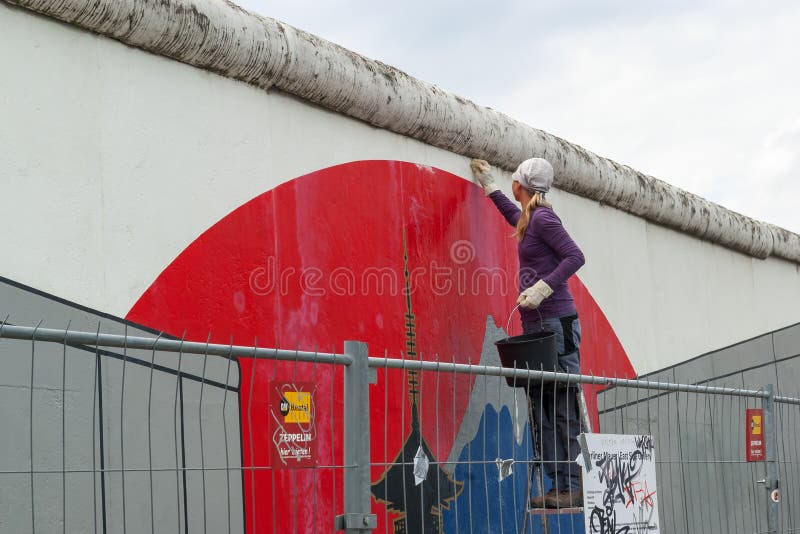 En ung flicka gör ren Berlin Wall, East Side Gallery, Berlin arkivbilder En ung flicka gör ren Berlin Wall, East Side Gallery, Berlin arkivbilder