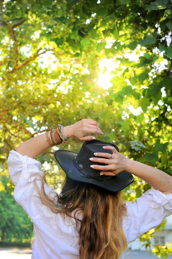 En ung hipster-kvinna har vila i stadsparken, soldag, lädersvart hatt utan ansikte arkivbilder En ung hipster-kvinna har vila i stadsparken, soldag, lädersvart hatt utan ansikte arkivbilder
