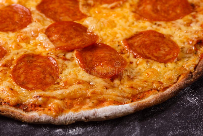 En ung kvinna i en grå aprong förbereder en pepperonpizza arkivfoton