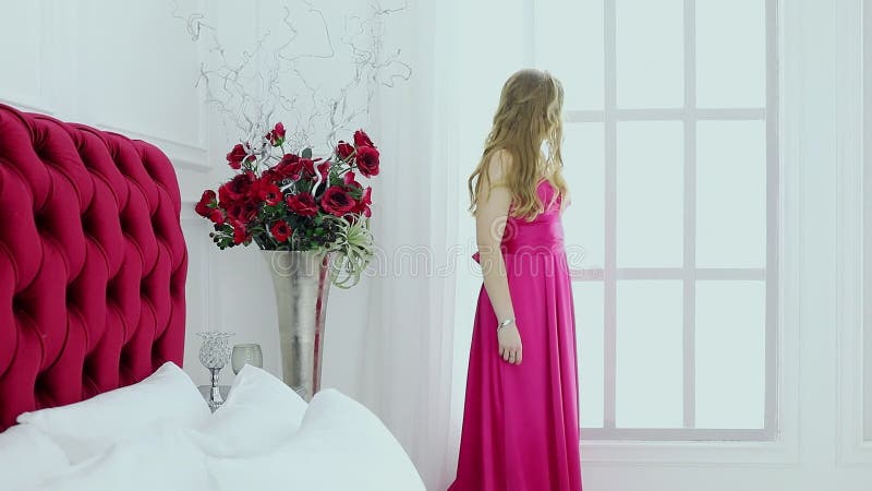 En ung kvinna i rödklädstativ nära blommor och arkivfilmer