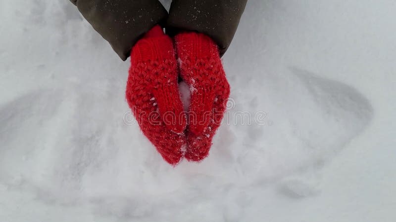 En ung kvinna på vintern, stickade ylletspissar kulminerar ut ett hjärta ur snö. valentinskt presentkoncept. uttrycksuttryck för k