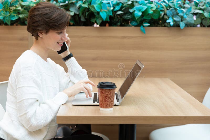 En ung kvinna som arbetar med en bärbar dator och dricker kaffe fotografering för bildbyråer