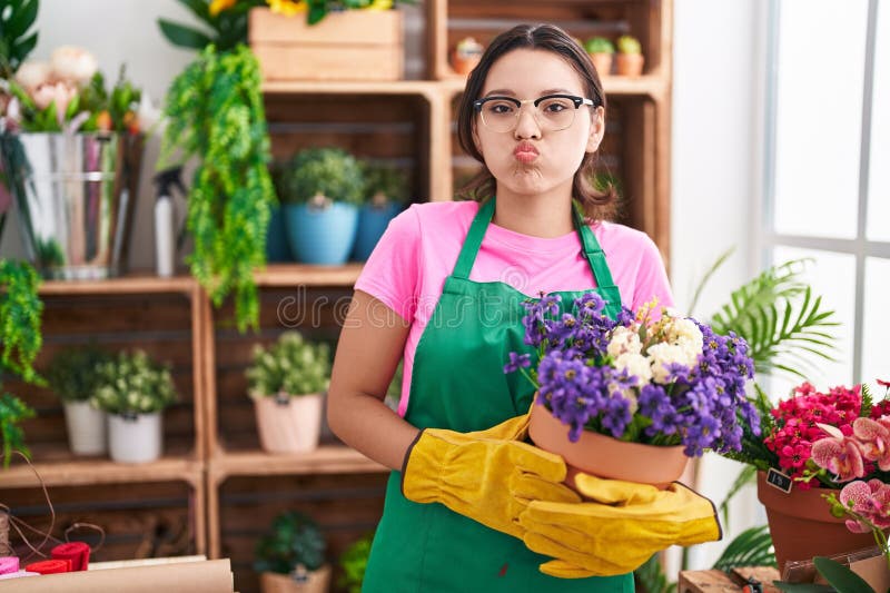 En ung kvinna som jobbar på en florist-butik och tittar på kameran och blåser en kyss som är underbar och sexig royaltyfri fotografi