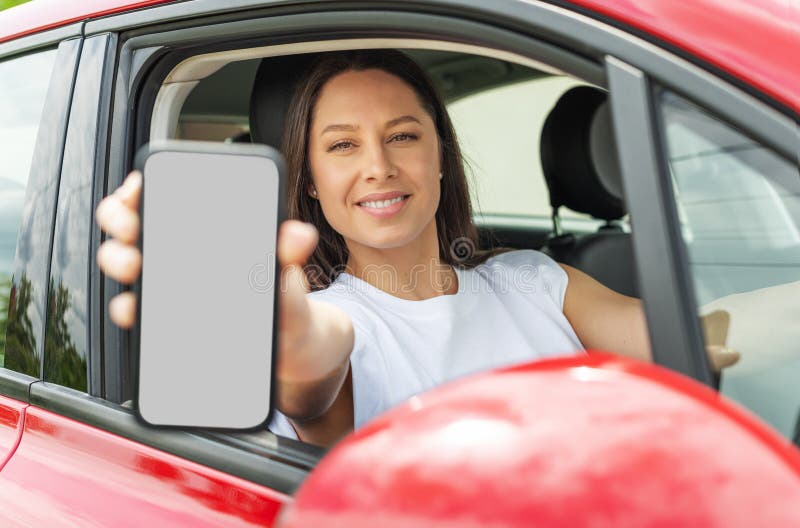 En ung kvinna som kör bil visar en smartphone-skärm. arkivfoton