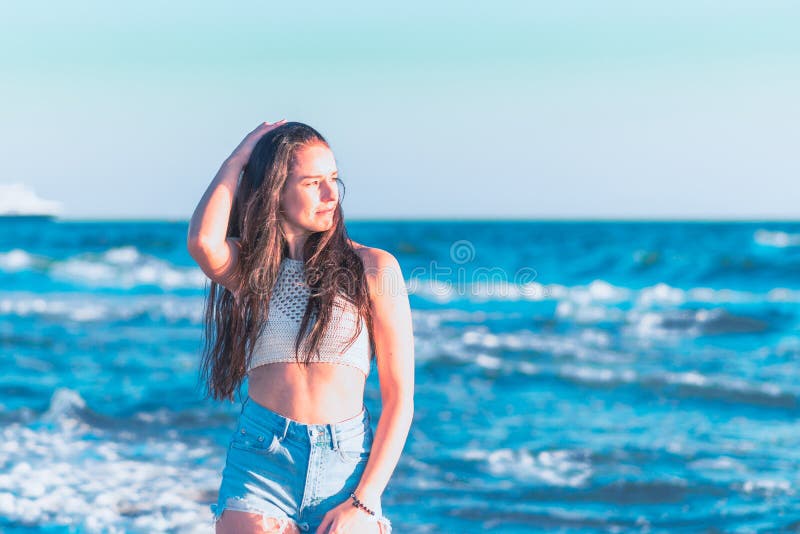 En ung kvinna som leker i havsöarna och njuter av att ha kul på sommarstranden i havsvatten fotografering för bildbyråer
