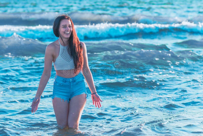 En ung kvinna som leker i havsöarna och njuter av att ha kul på sommarstranden i havsvatten arkivbild