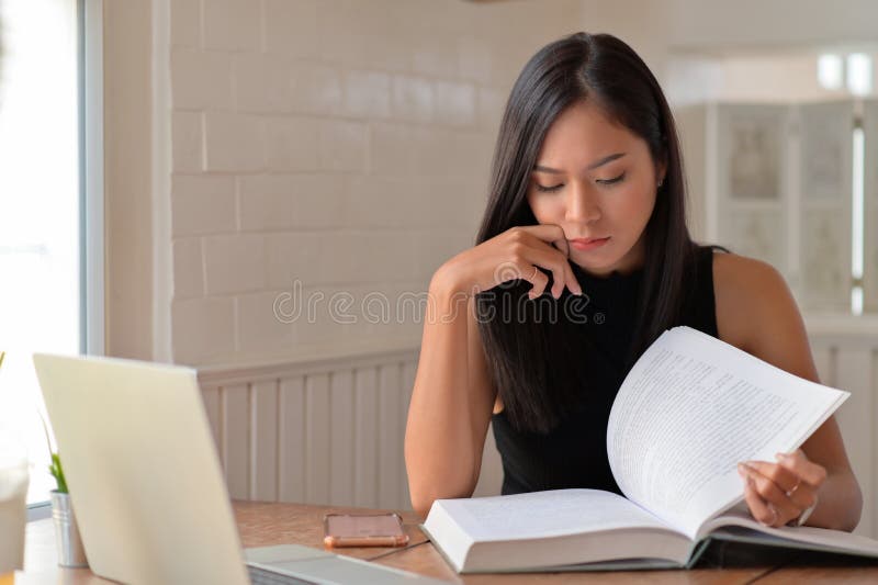 En ung kvinna som läste med ett seriöst uttryck som hon förberedde sig för inträdesprovet till högskolan fotografering för bildbyråer