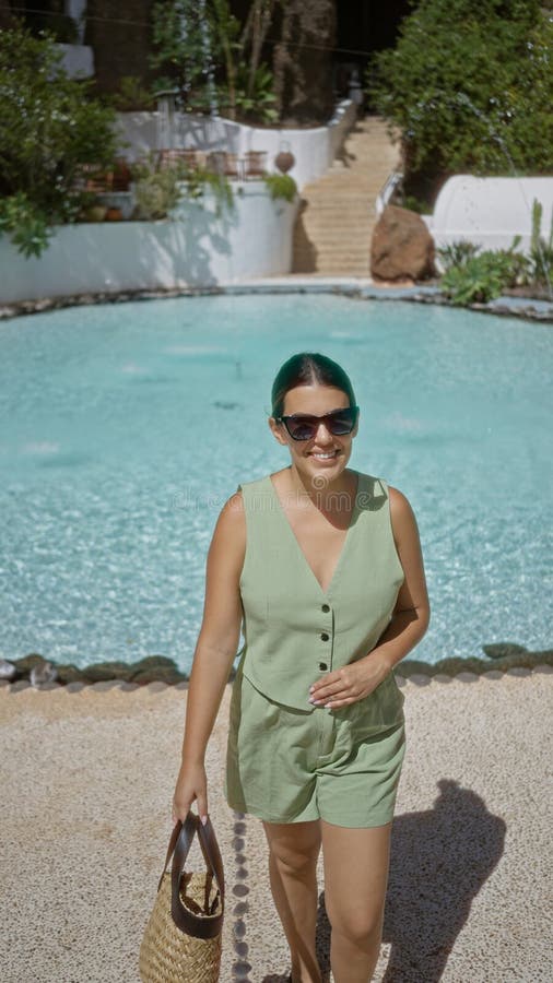 En ung kvinna som står vid en scenpool i lagomar lanzarote och som har en solnydag på Kanarieöarna arkivbild