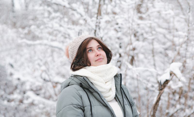 En ung kvinna som tittar upp på vinternaturen är en vacker flicka bland träd täckta med snö som går i vit skog och njuter av arkivbild