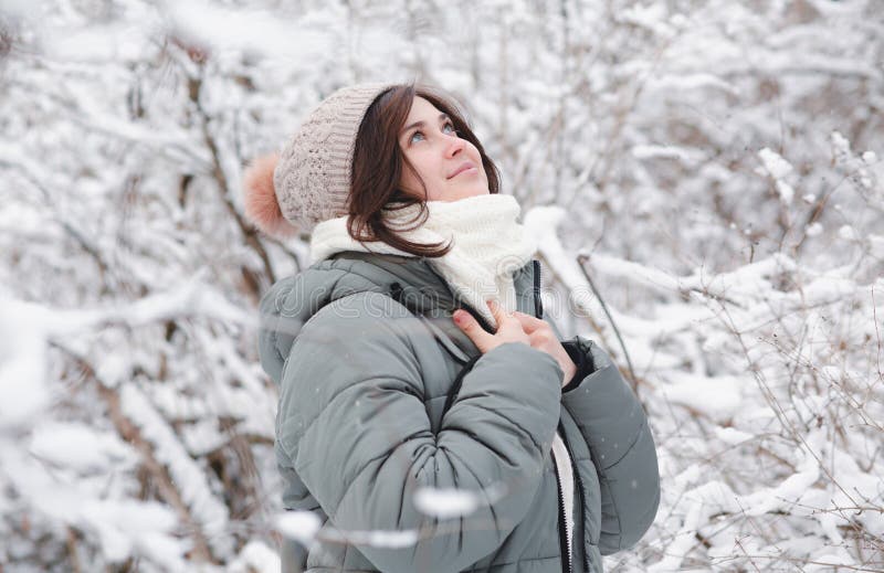 En ung kvinna som tittar upp på vinternaturen är en vacker flicka bland träd täckta med snö som går i vit skog och njuter av royaltyfria foton