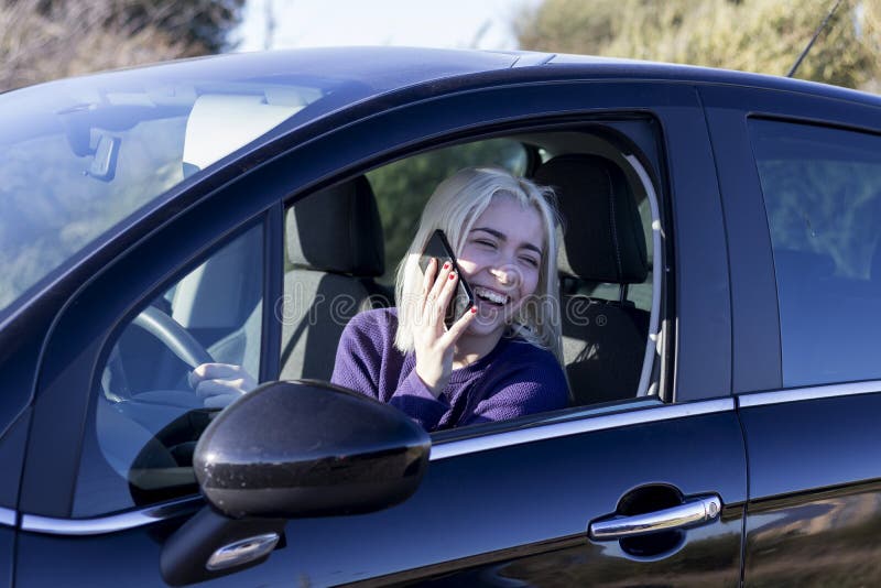 En ung kvinnlig chaufför som pratar med telefon i bilen fotografering för bildbyråer
