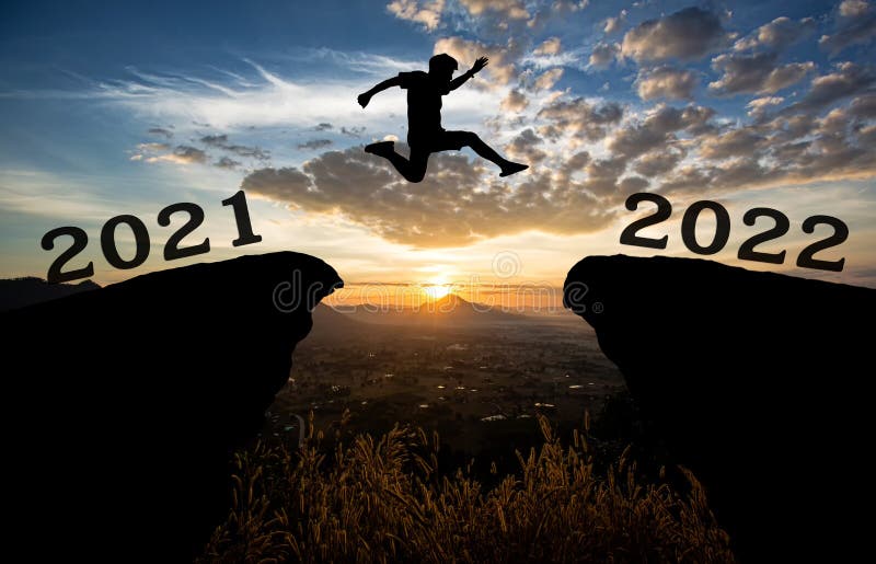 En ung man hoppar mellan 2021 och 2022 år över solen och genom på gapet på nattfärgat himmel i berggrunden glad