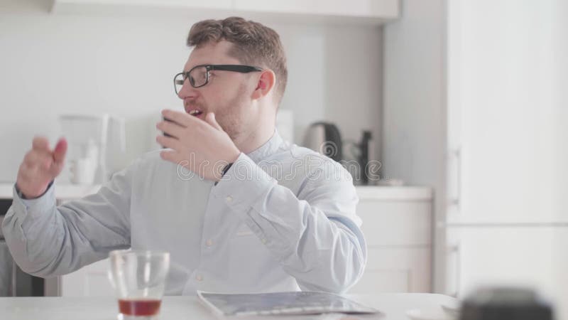 En ung man i glasögon och snygga kläder kommunicerar över en homemad frukost