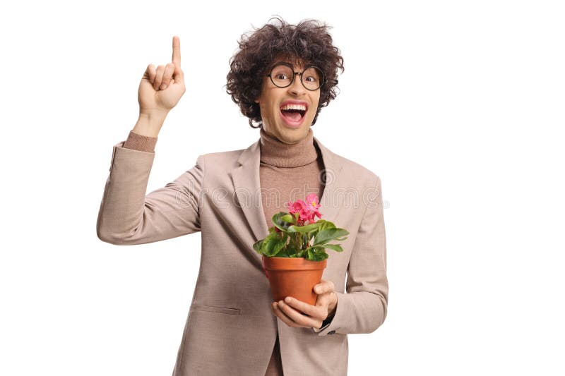 En ung man som har en blomma i en kruka och som pekar uppåt arkivfoton