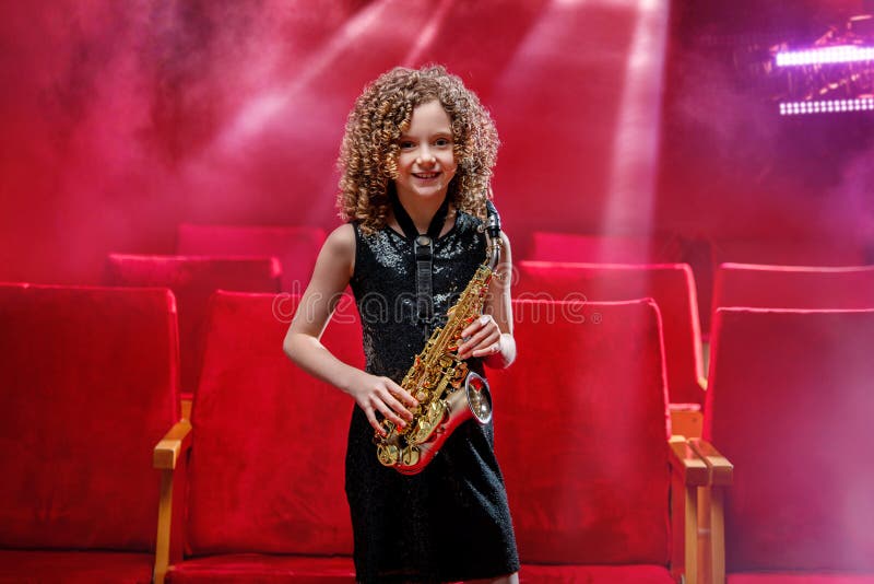 En ung musiker-flicka har saxofon och leenden. royaltyfria foton