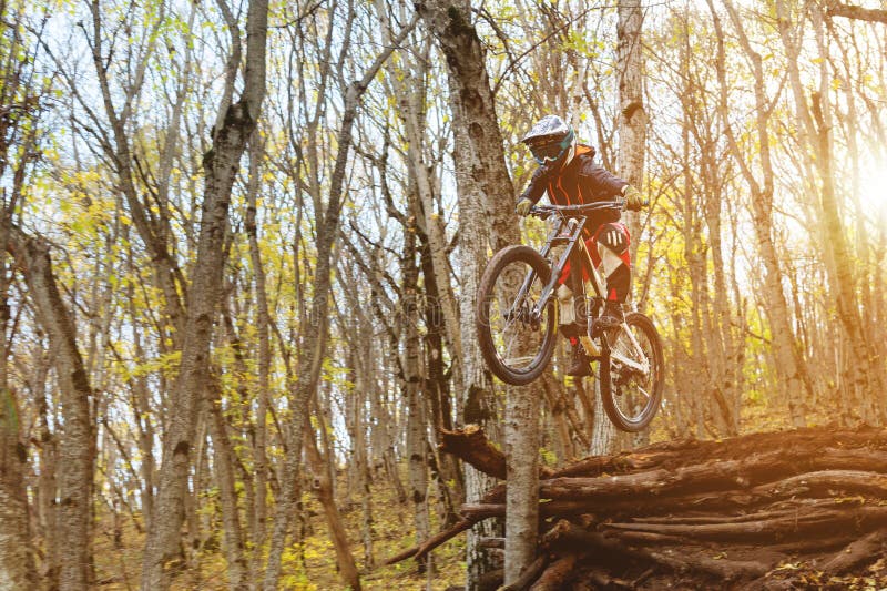 En ung ryttare på hjulet av hans mountainbike gör ett trick i banhoppning på språngbrädan av det sluttande berget royaltyfri fotografi En ung ryttare på hjulet av hans mountainbike gör ett trick i banhoppning på språngbrädan av det sluttande berget royaltyfri fotografi