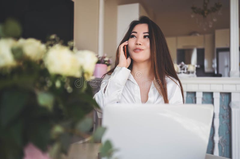 En ung, vacker affärskvinna som arbetar online med en bärbar dator placerad vid bordet på hemkontoret. leende arkivfoto
