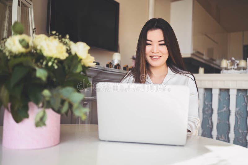 En ung, vacker affärskvinna som arbetar online med en bärbar dator placerad vid bordet på hemkontoret. leende arkivbild