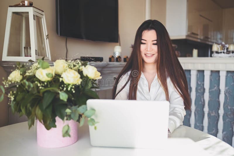 En ung, vacker affärskvinna som arbetar online med en bärbar dator placerad vid bordet på hemkontoret. leende arkivbilder