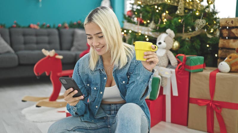 En ung, vacker historisk kvinna som använder smartphone och dricker kaffe för att fira jul hemma royaltyfria bilder