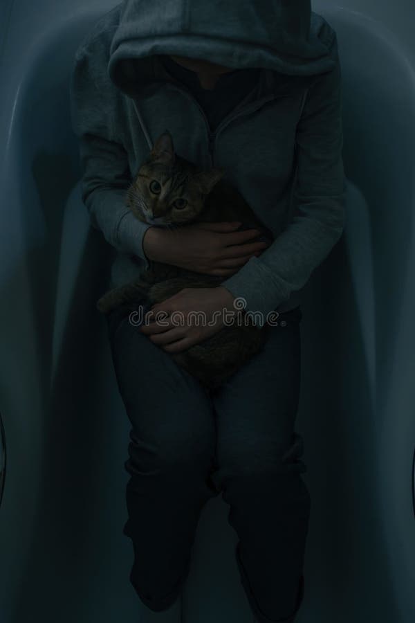 En upprörd kvinna i kläderna ligger i badrummet med katten som lugnar ner sin ägare. arkivbilder En upprörd kvinna i kläderna ligger i badrummet med katten som lugnar ner sin ägare. arkivbilder