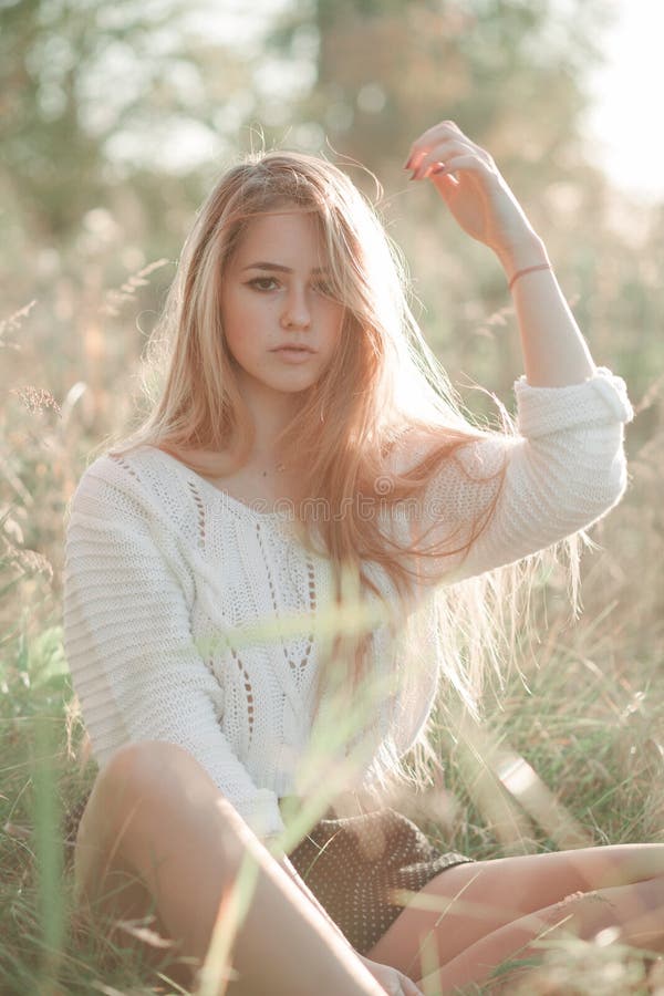En vacker tjej som sitter pÃ¥ fältet och tittar in i kameran fotografering för bildbyråer En vacker tjej som sitter pÃ¥ fältet och tittar in i kameran fotografering för bildbyråer
