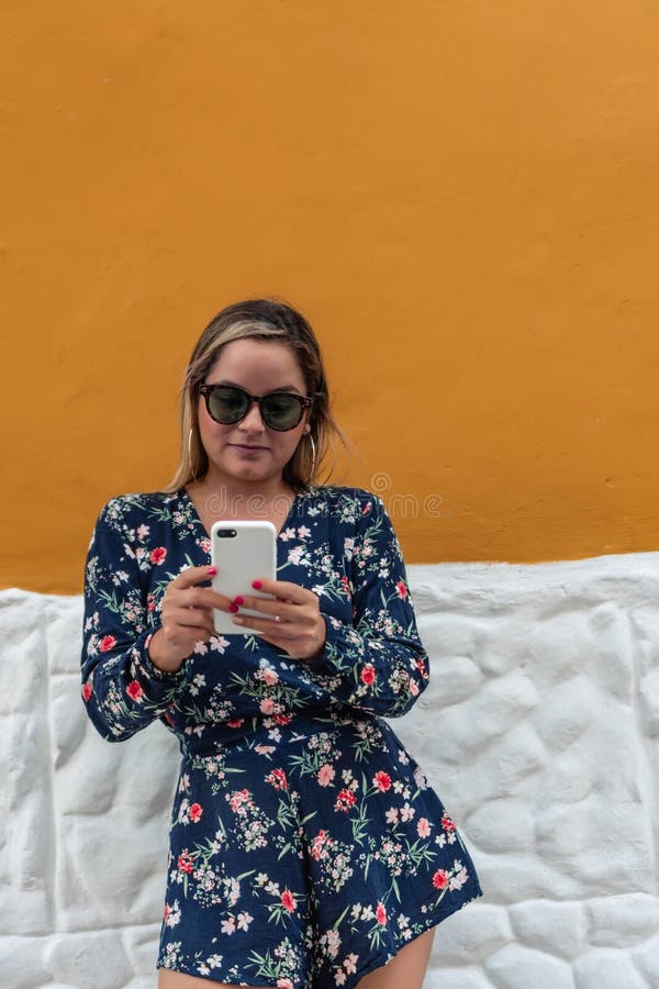 En vacker ung kvinna som tar en selfie eller använder en telefon utomhus.