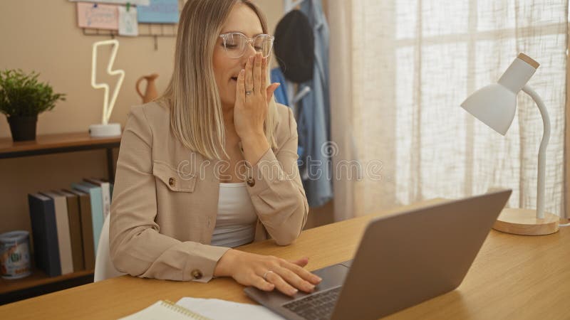 En vacker, vuxen blond kvinna på ett hemmakontor som längtar efter att arbeta med en bärbar dator i ett starkt inomhusrum fotografering för bildbyråer