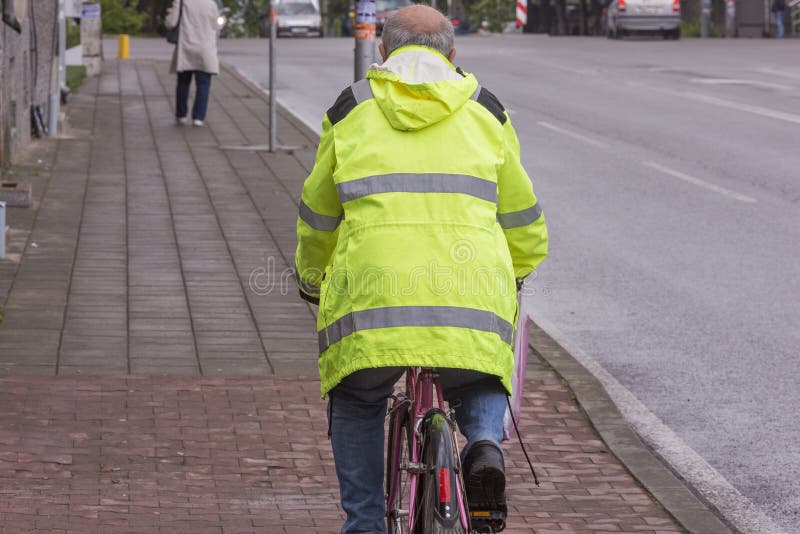 En vuxen cyklist rider en cykel på trottoaren arkivfoton En vuxen cyklist rider en cykel på trottoaren arkivfoton