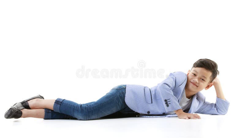 En 10-årig asiansk pojke i en tillfällig kavaj ligger på golvet och ler glatt i gott humör när man tittar på kameran.